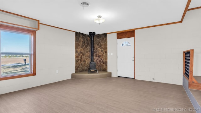 unfurnished living room featuring hardwood / wood-style flooring, a wood stove, and ornamental molding