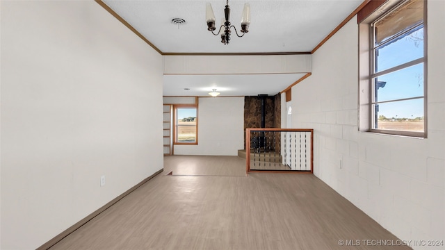 empty room with hardwood / wood-style flooring, a notable chandelier, and crown molding