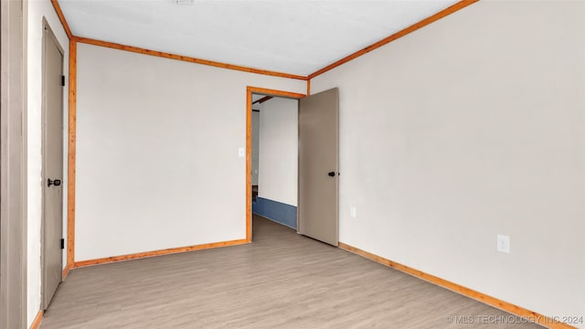 empty room featuring crown molding and light hardwood / wood-style flooring