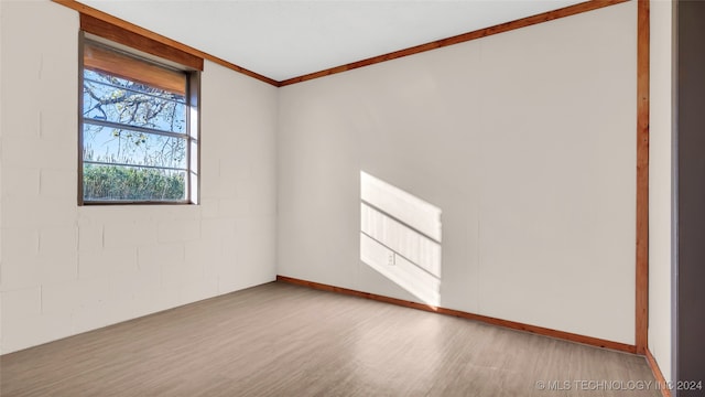 empty room with light wood-type flooring and crown molding