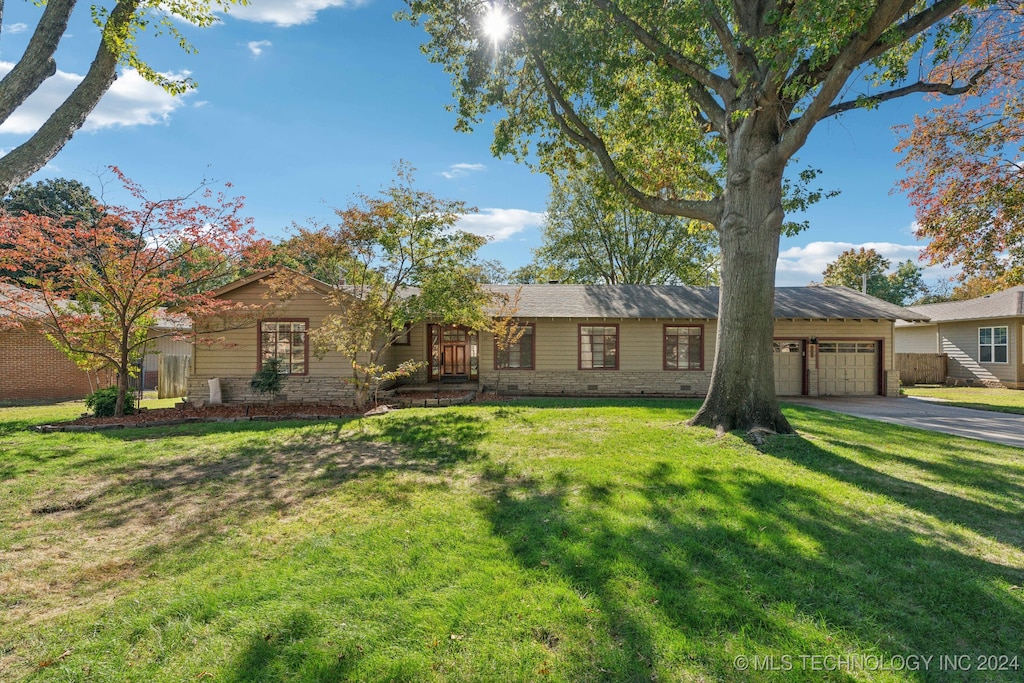 ranch-style house with a garage and a front lawn