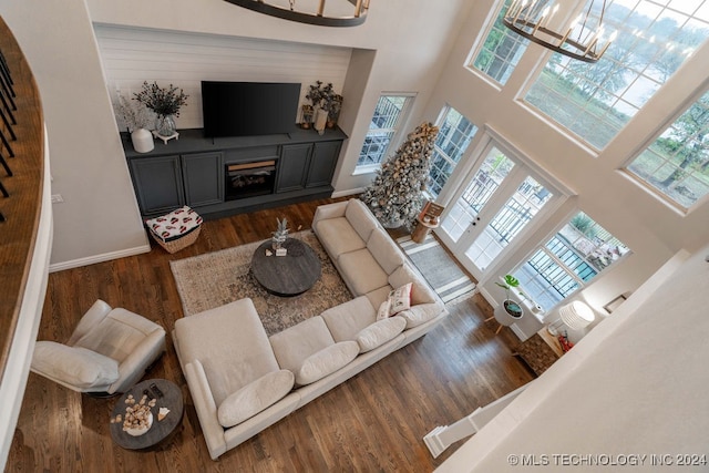 living room featuring dark hardwood / wood-style flooring, a towering ceiling, and a notable chandelier