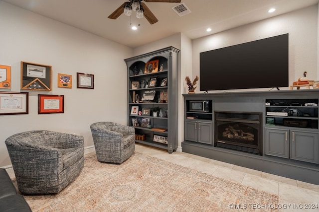 living area with ceiling fan and light tile patterned flooring