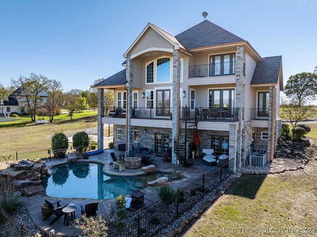 back of property with french doors, a balcony, a patio area, a yard, and a fenced in pool