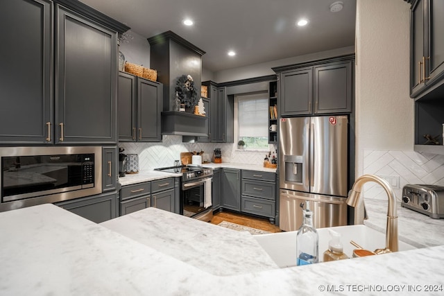 kitchen with decorative backsplash, appliances with stainless steel finishes, light stone counters, and sink