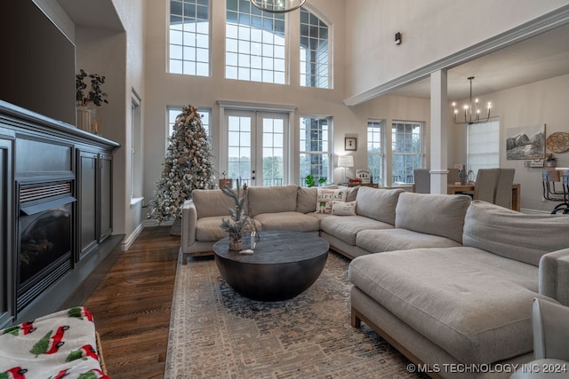 living room with a chandelier, french doors, a towering ceiling, and dark wood-type flooring