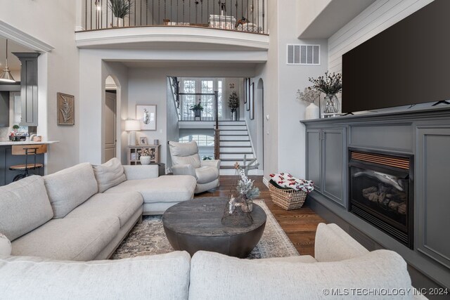 living room featuring dark wood-type flooring and a high ceiling