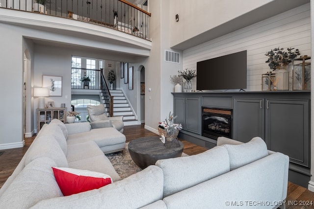 living room with a towering ceiling and dark hardwood / wood-style floors