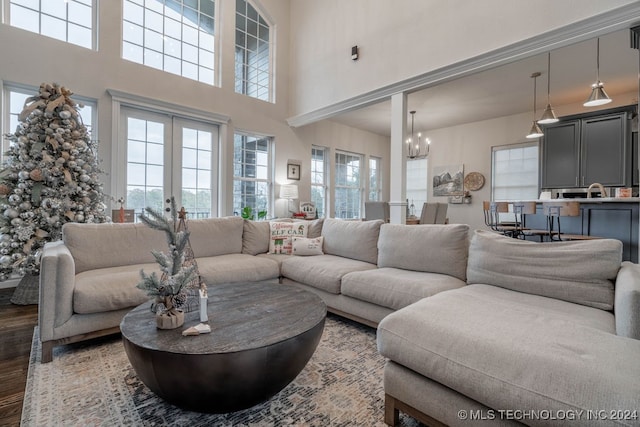 living room featuring dark hardwood / wood-style flooring, a high ceiling, plenty of natural light, and a notable chandelier