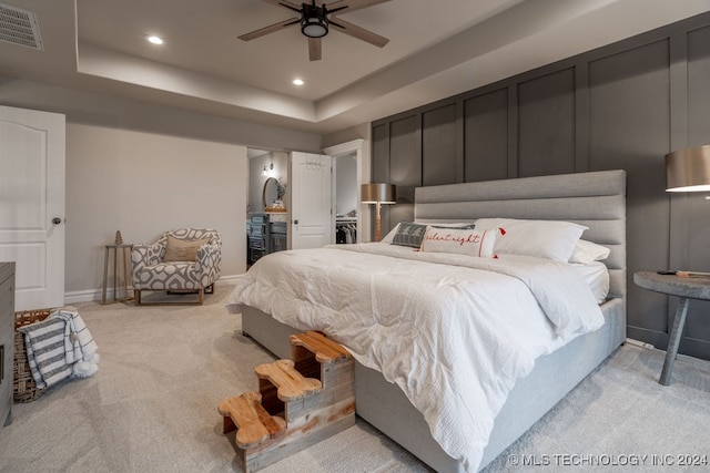 carpeted bedroom with ceiling fan and a tray ceiling