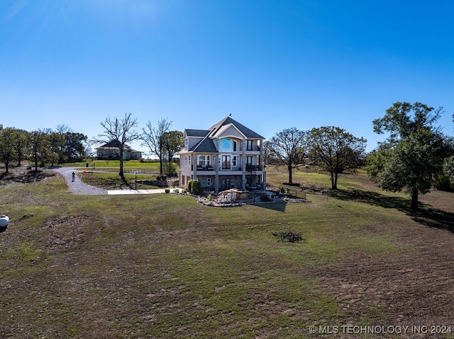 view of front of house with a balcony and a front lawn