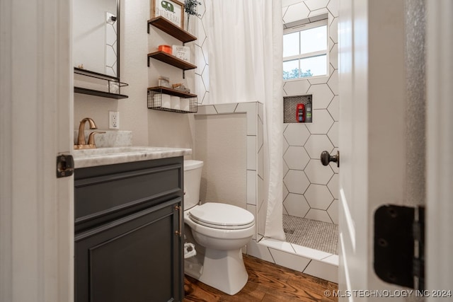 bathroom with vanity, toilet, wood-type flooring, and tiled shower