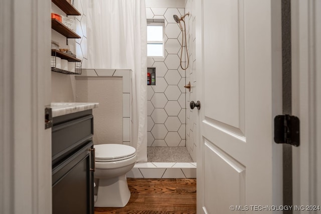 bathroom with toilet, vanity, wood-type flooring, and tiled shower