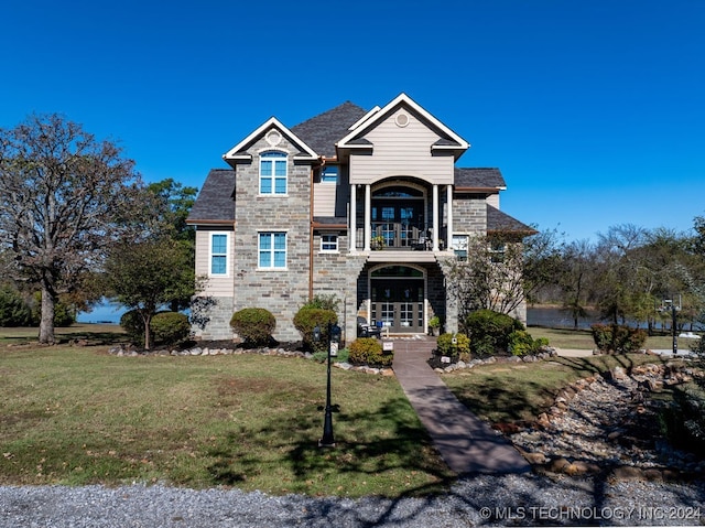 view of front of property with french doors, a balcony, and a front lawn