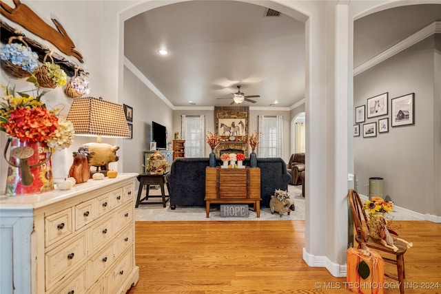 bedroom featuring a large fireplace, light hardwood / wood-style floors, and crown molding