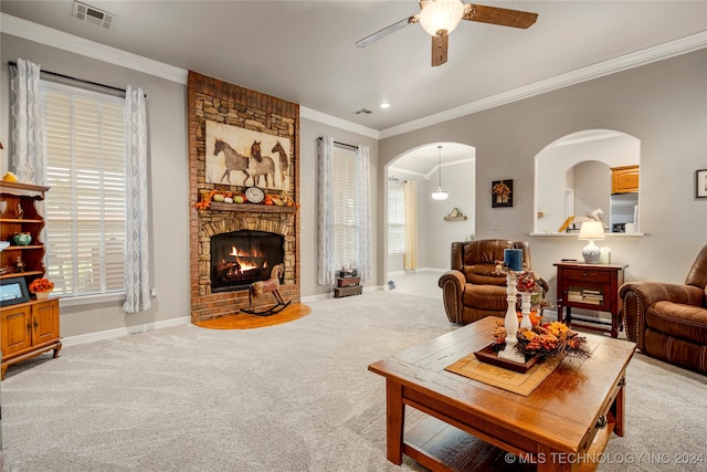 living room with light colored carpet, a stone fireplace, ceiling fan, and ornamental molding