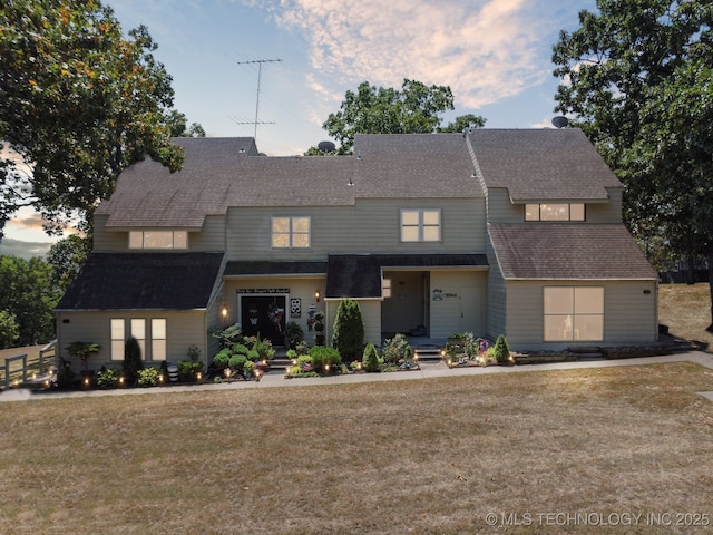 view of front of home with roof with shingles and a front yard