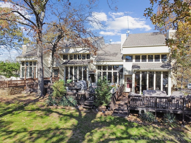 back of house featuring a wooden deck, a lawn, and a sunroom