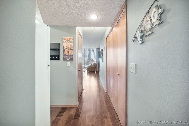 corridor with hardwood / wood-style flooring and a textured ceiling