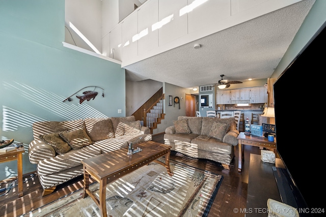 living room with a textured ceiling, ceiling fan, hardwood / wood-style floors, and a high ceiling