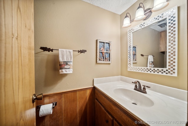 bathroom featuring vanity, a textured ceiling, and wooden walls