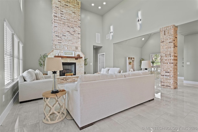 684 Chateau Bnd, Ardmore, OK 73401 - living area with a high ceiling, decorative columns, a brick fireplace, recessed lighting, and light marble finish floors