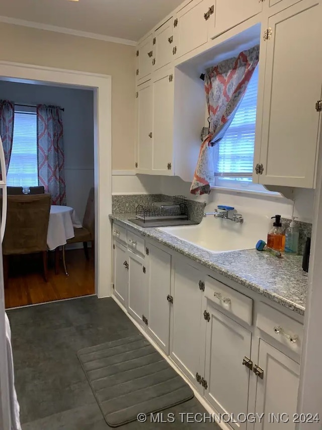 kitchen featuring white cabinetry, sink, light stone counters, dark hardwood / wood-style flooring, and ornamental molding