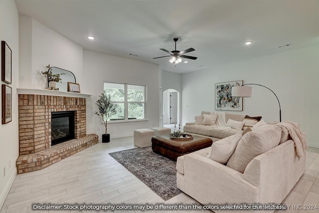 living room with light hardwood / wood-style flooring, a brick fireplace, and ceiling fan