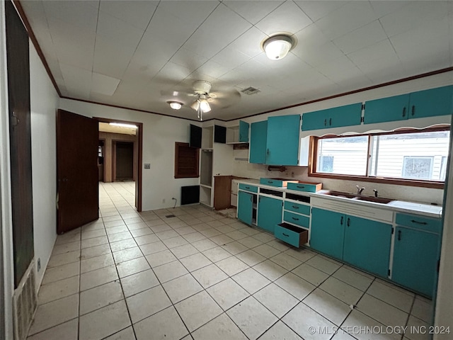 kitchen featuring ceiling fan, sink, blue cabinets, light tile patterned floors, and ornamental molding