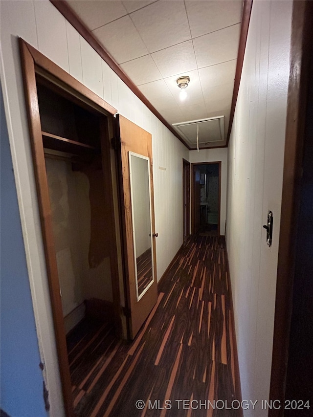 hallway featuring dark hardwood / wood-style floors, crown molding, and wooden walls