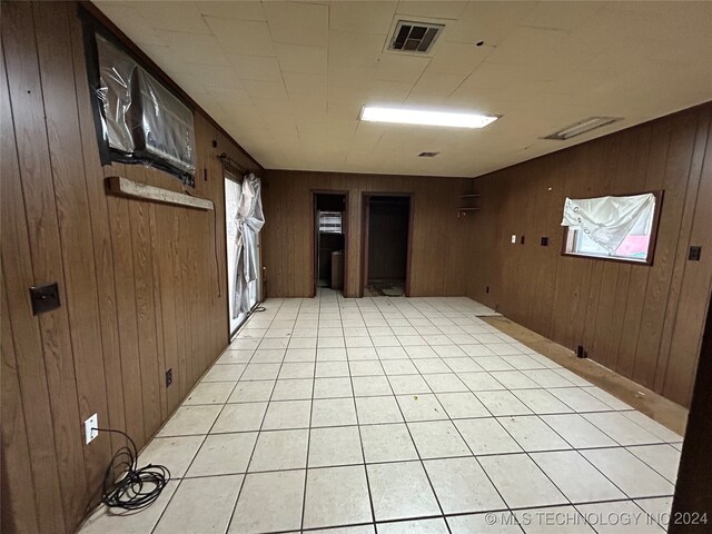 unfurnished room featuring wooden walls and light tile patterned floors