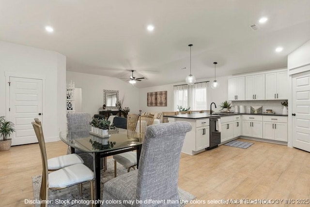 kitchen featuring white cabinets, dark countertops, open floor plan, hanging light fixtures, and light wood-style floors