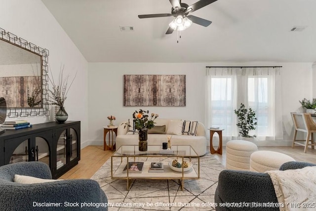 living area featuring baseboards, light wood-style flooring, visible vents, and a ceiling fan