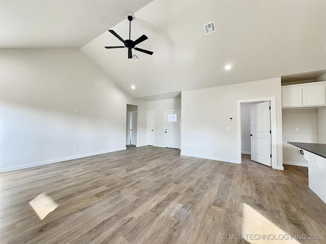 unfurnished living room featuring baseboards, visible vents, a ceiling fan, light wood-style flooring, and high vaulted ceiling