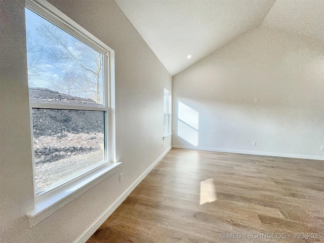 empty room featuring baseboards, vaulted ceiling, and wood finished floors