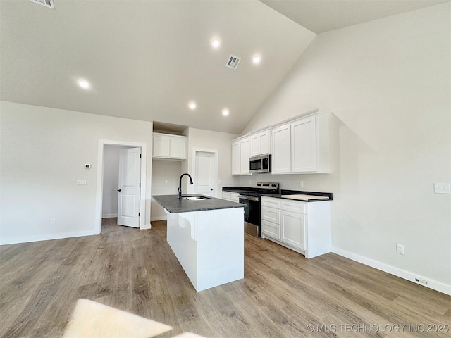 kitchen with white cabinets, an island with sink, light wood-style flooring, appliances with stainless steel finishes, and a sink