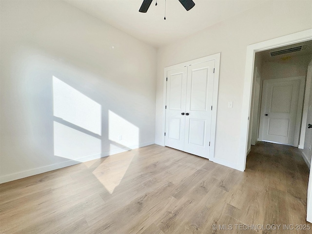 unfurnished bedroom with a closet, visible vents, ceiling fan, light wood-type flooring, and baseboards