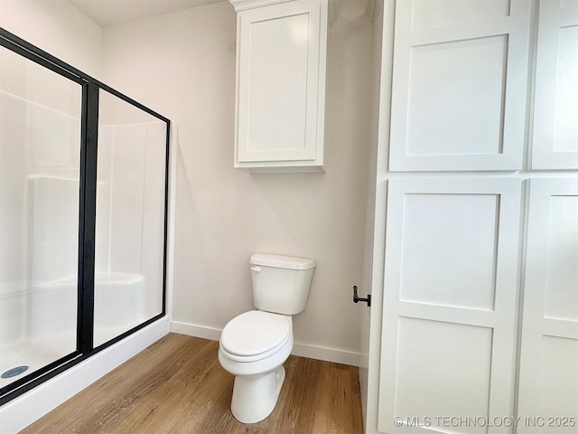 full bathroom featuring toilet, a stall shower, baseboards, and wood finished floors