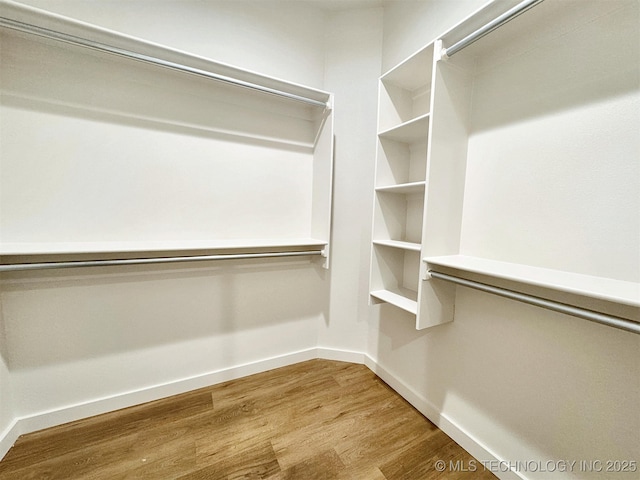 walk in closet with wood finished floors