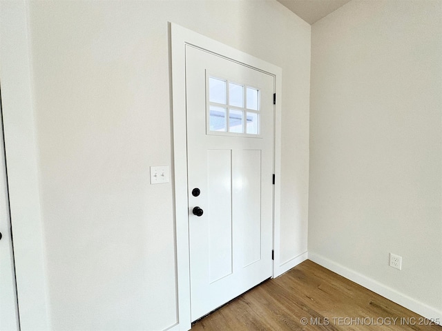 doorway featuring baseboards and wood finished floors