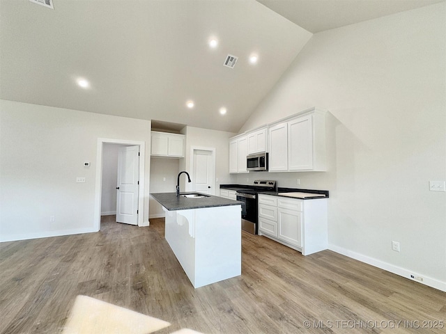 890 E Harlan Dr, Tahlequah, OK 74464 - kitchen with a sink, dark countertops, an island with sink, light wood-style flooring, and appliances with stainless steel finishes