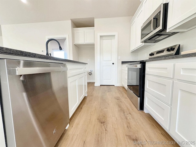 890 E Harlan Dr, Tahlequah, OK 74464 - kitchen with white cabinets, dark countertops, stainless steel appliances, and light wood-type flooring