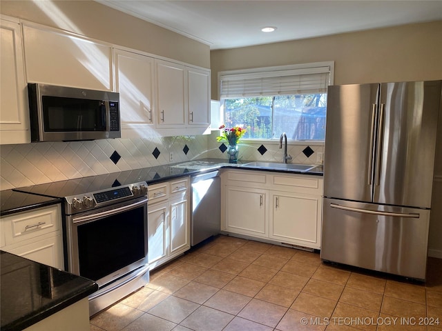 kitchen featuring white cabinets, sink, decorative backsplash, light tile patterned floors, and stainless steel appliances