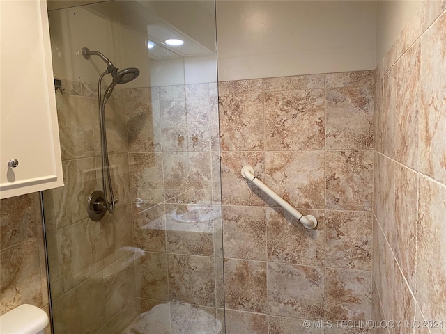 bathroom featuring a tile shower and toilet