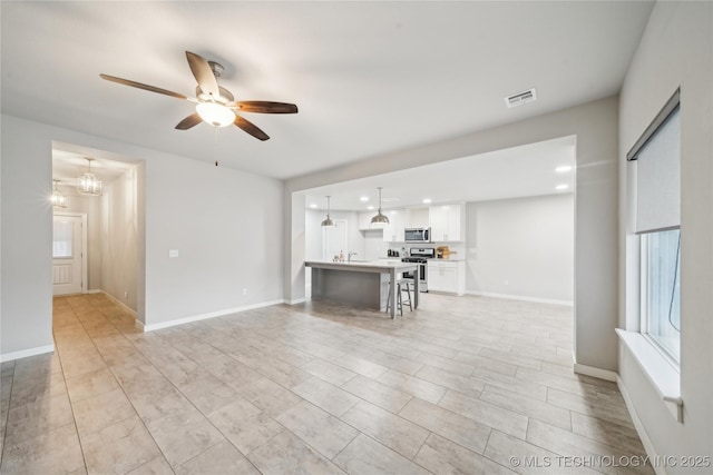 unfurnished living room featuring ceiling fan with notable chandelier