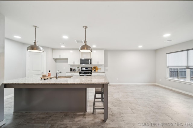 kitchen featuring white cabinets, decorative light fixtures, light stone counters, and stainless steel appliances