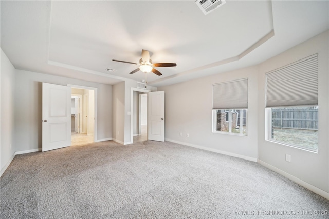 unfurnished bedroom featuring a raised ceiling, ceiling fan, and carpet floors