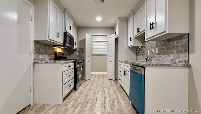 kitchen with white cabinets, light hardwood / wood-style floors, light stone countertops, and stainless steel appliances