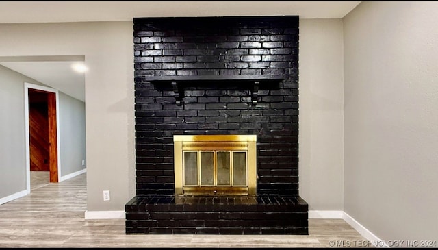 interior details with hardwood / wood-style floors and a brick fireplace