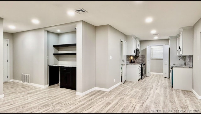 kitchen featuring sink, tasteful backsplash, appliances with stainless steel finishes, white cabinets, and light wood-type flooring